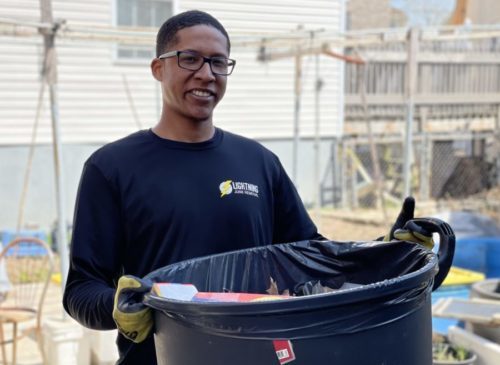 junk removal pro smiling while holding trash bin