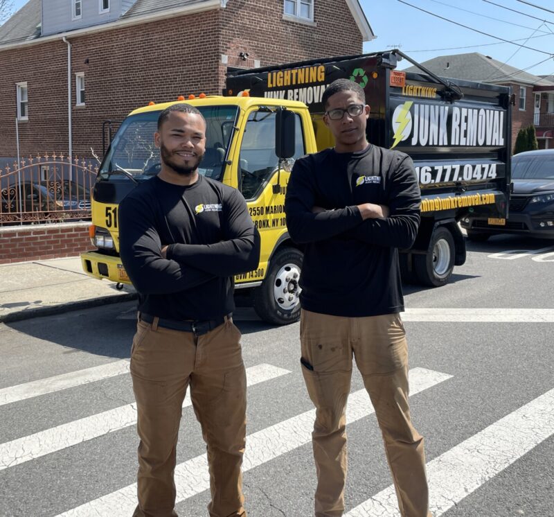 Junk removal professionals posing in front of the truck ready to provide property management services
